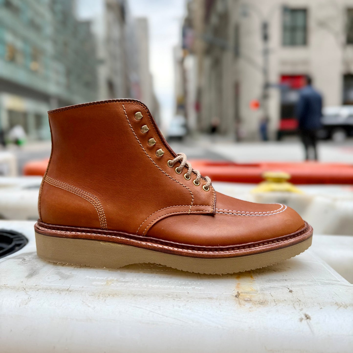 The Alden Madison 40311H Sherwood Indy Boot, made from Saddle Calf Leather with white stitching and a Cream Wedge Sole, is shown outdoors against a blurred city street backdrop.