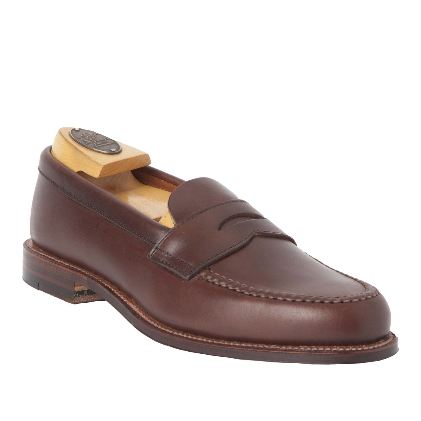 The Alden Madison 17831F - Unlined Leisure Hand Sewn in Brown Chromexcel loafer is angled with a wooden shoe tree inside, featuring a sleek design, unlined flex for comfort, edge stitching, and a low heel with a sturdy leather sole.