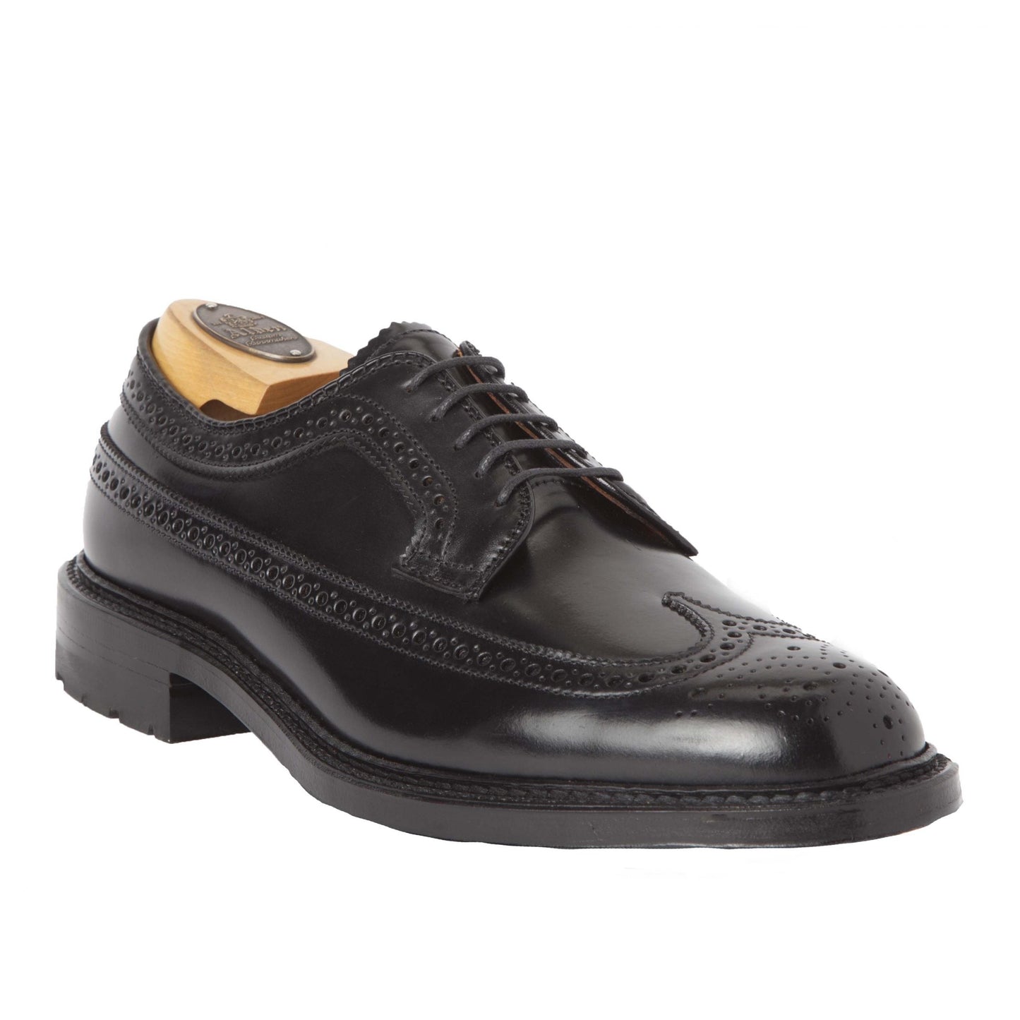 The Alden Madison 9751C Long Wing Blucher features black shell cordovan leather with brogue detailing and laces. With a polished finish, wooden shoe tree, and robust commando sole for durability, it is showcased on a plain white background.