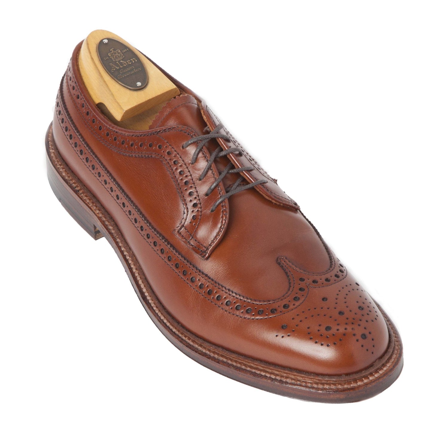 A single Alden Madison 979 Long Wing Blucher in burnished tan calfskin, adorned with intricate perforations and laces, rests on a Double Oak Leather Outsole. Crafted using the Barrie Last, it is displayed at an angle on a white background.