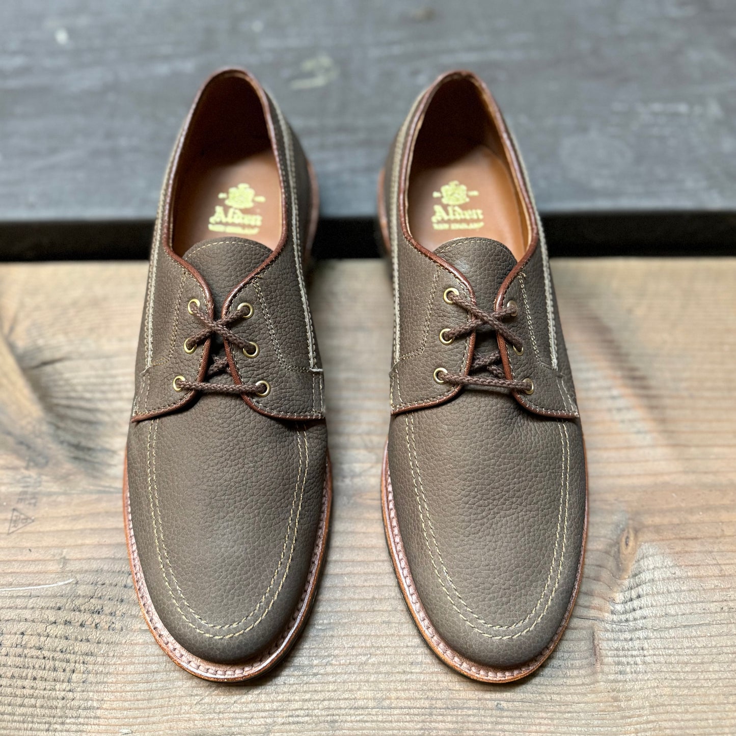Alden Madison’s 7351 - Ivy Blucher in Clay Nubuck leather with tan stitching are lace-up dress shoes shown side by side on a wooden surface.