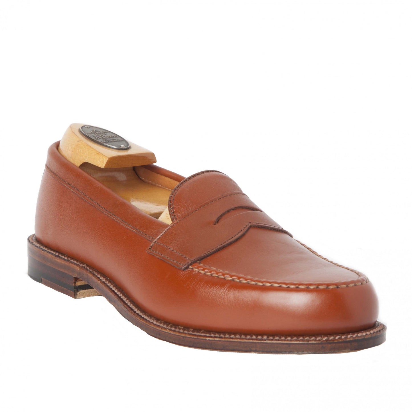 Alden Madisons 983 - Leisure Hand Sewn loafer in burnished tan calfskin features a classic penny strap and meticulous stitching, crafted on the Van Last with a single oak leather outsole, displayed with a wooden shoe tree against a plain white backdrop.