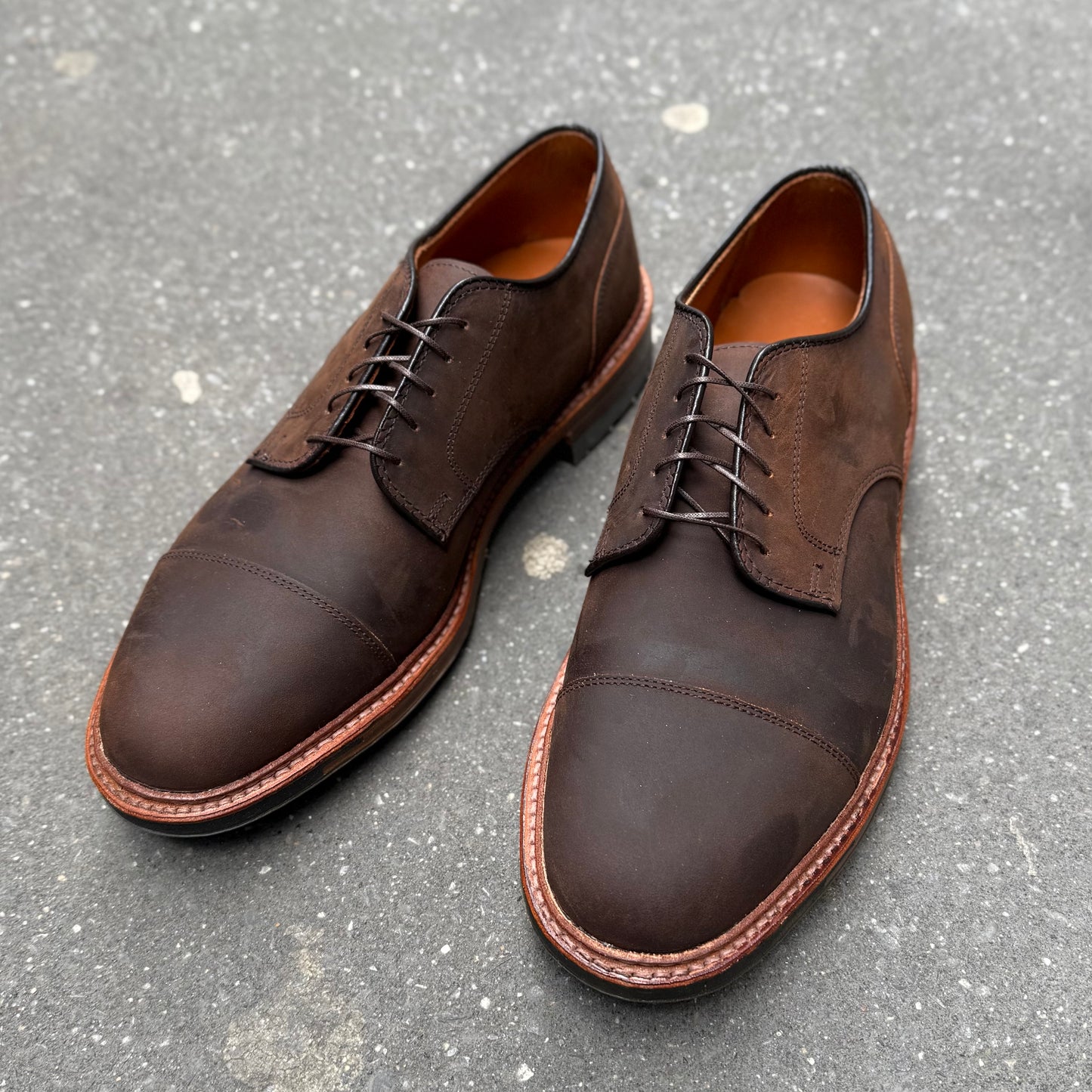 The Alden Madison D4519C Tobacco Chamois Cap Toe Blucher, with visible laces and stitching, rests on a textured gray surface. The Blucher style features a rounded toe and light brown sole, adding sophistication to any attire.