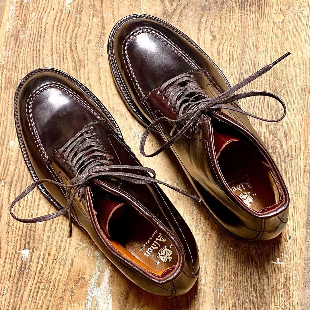 Alden Madisons 40508HC - Color 8 Shell Indy Boot boasts a dark brown leather construction with a glossy finish, visible edge stitching, and a Commando Sole for superior grip. Elegantly laced and exuding timeless style, these boots are displayed side by side on a wooden floor.