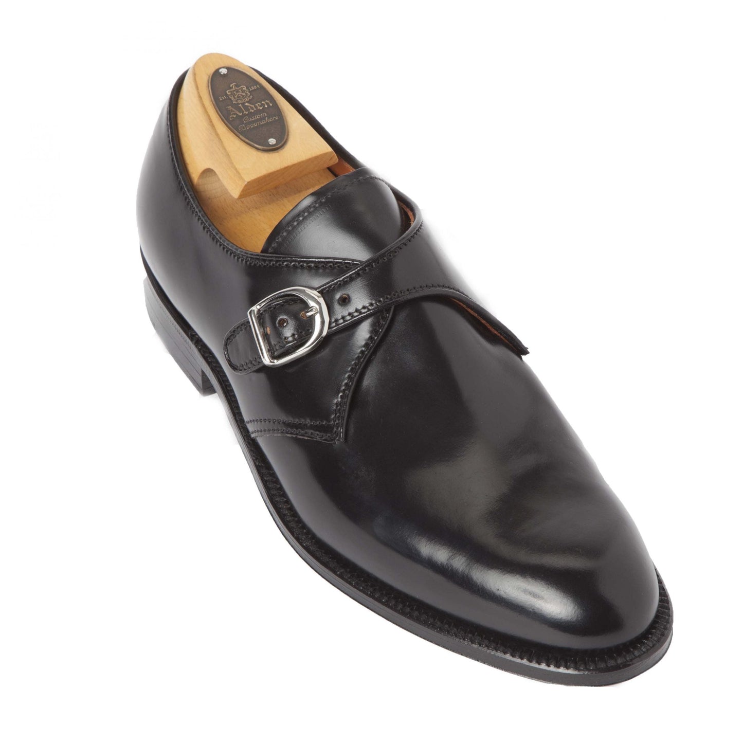 The Alden Madison 1655 - Monk Strap Black in Shell Cordovan shoe showcases a polished finish, a leather sole, and a striking nickel buckle. A wooden shoe tree is inserted to maintain its shape.