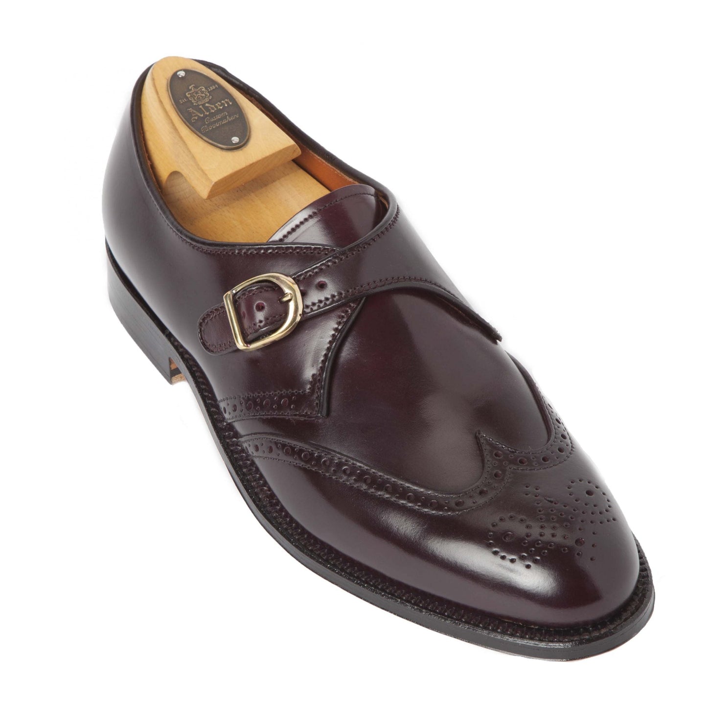 The Alden Madison 1671 is a single Wing Tip Monk Strap shoe, crafted in Color 8 Shell Cordovan with perforations and a buckle strap. Built on an Aberdeen Last for sleekness, its displayed with a wooden shoe tree inside.