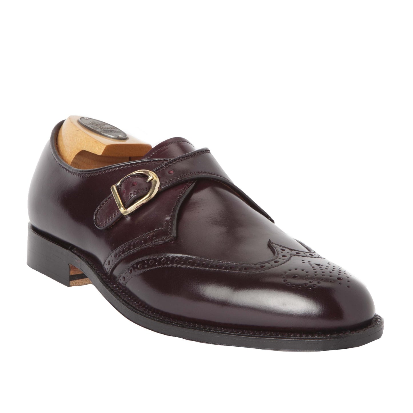 Alden Madisons 1671 Wing Tip Monk Strap is crafted in Color 8 Shell Cordovan with a brogue toe pattern, featuring a gold buckle and an inserted wooden shoe tree.