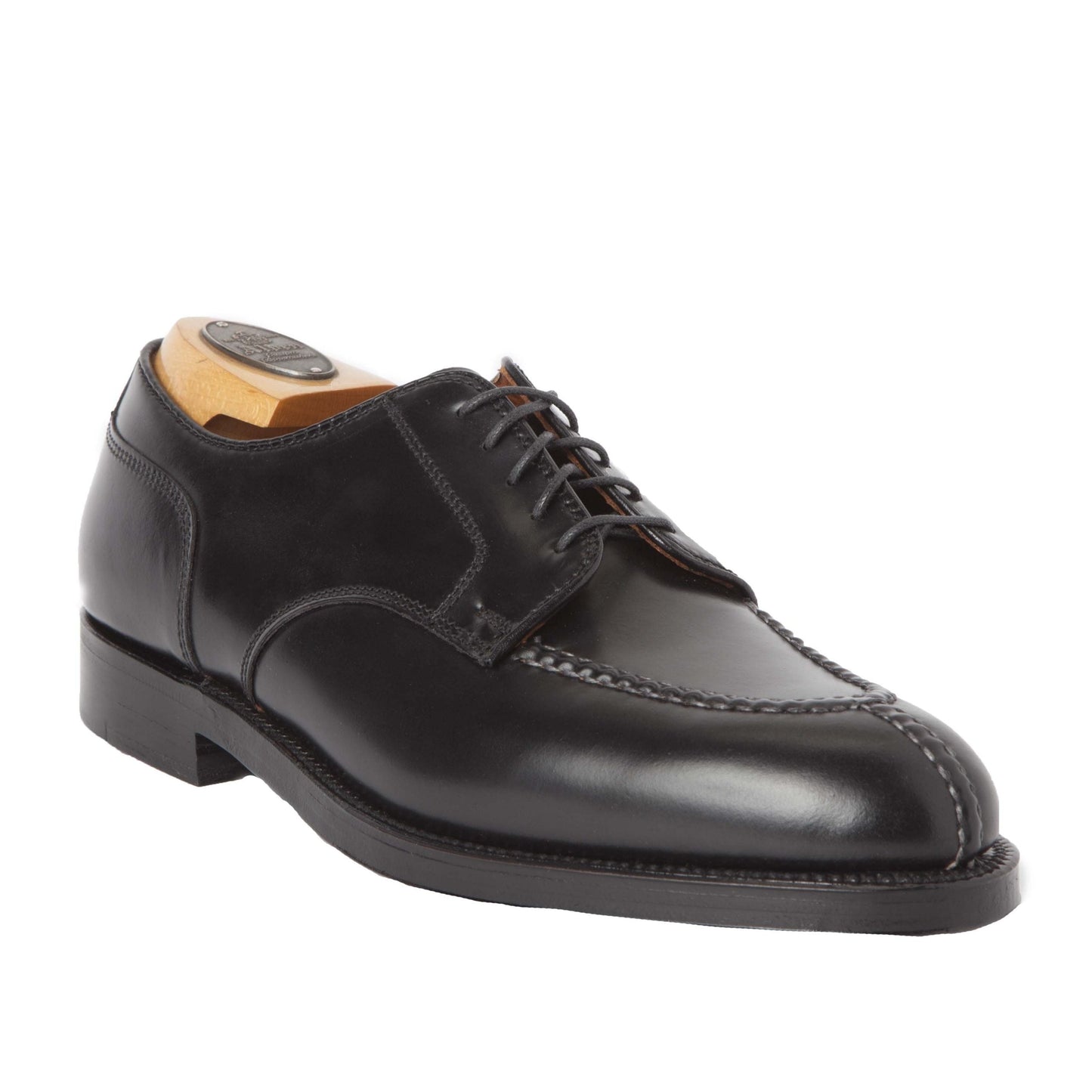 The Alden Madison 2211 Norwegian Split Toe Blucher in Black Shell Cordovan is a polished leather dress shoe with hand stitching and a lace-up design, displayed at an angle with a wooden shoe tree to maintain shape.