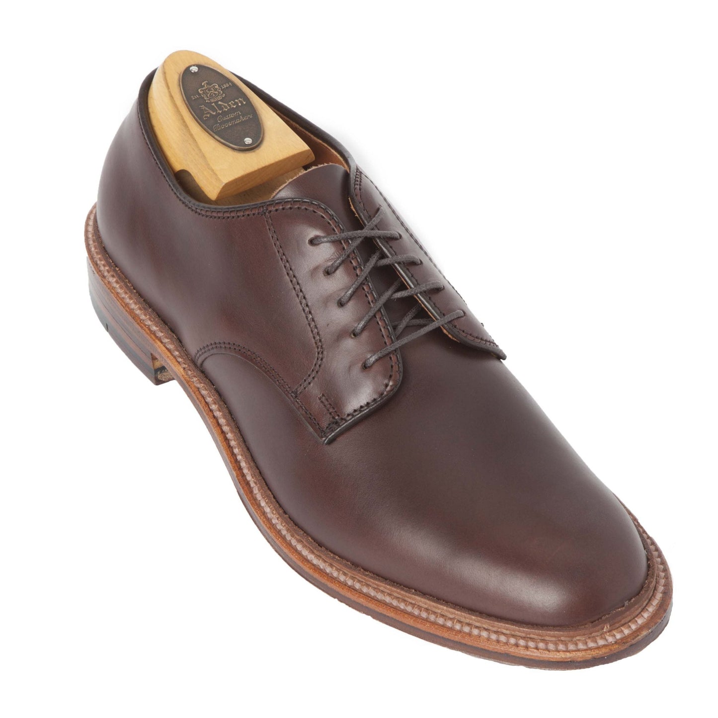 The Alden Madison 29364F Unlined Plain Toe Dover in brown Chromexcel features a single dark brown leather dress shoe with brown laces, wooden shoe tree, rounded toe, Barrie Last, and light brown welted leather sole.