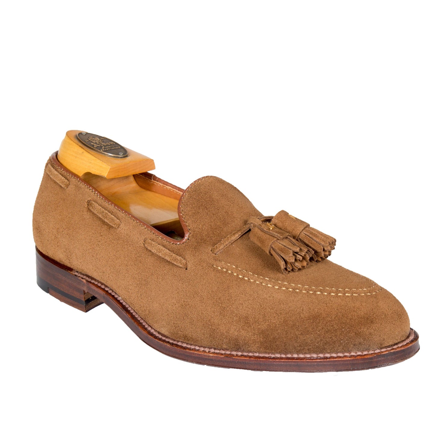 The Alden Madison 3403 Tassel Loafer in Snuff Suede features tassels on its front and sits on a wooden shoe tree; crafted on the Aberdeen Last, it boasts a smooth polished leather sole and heel, offering a refined and elegant look.