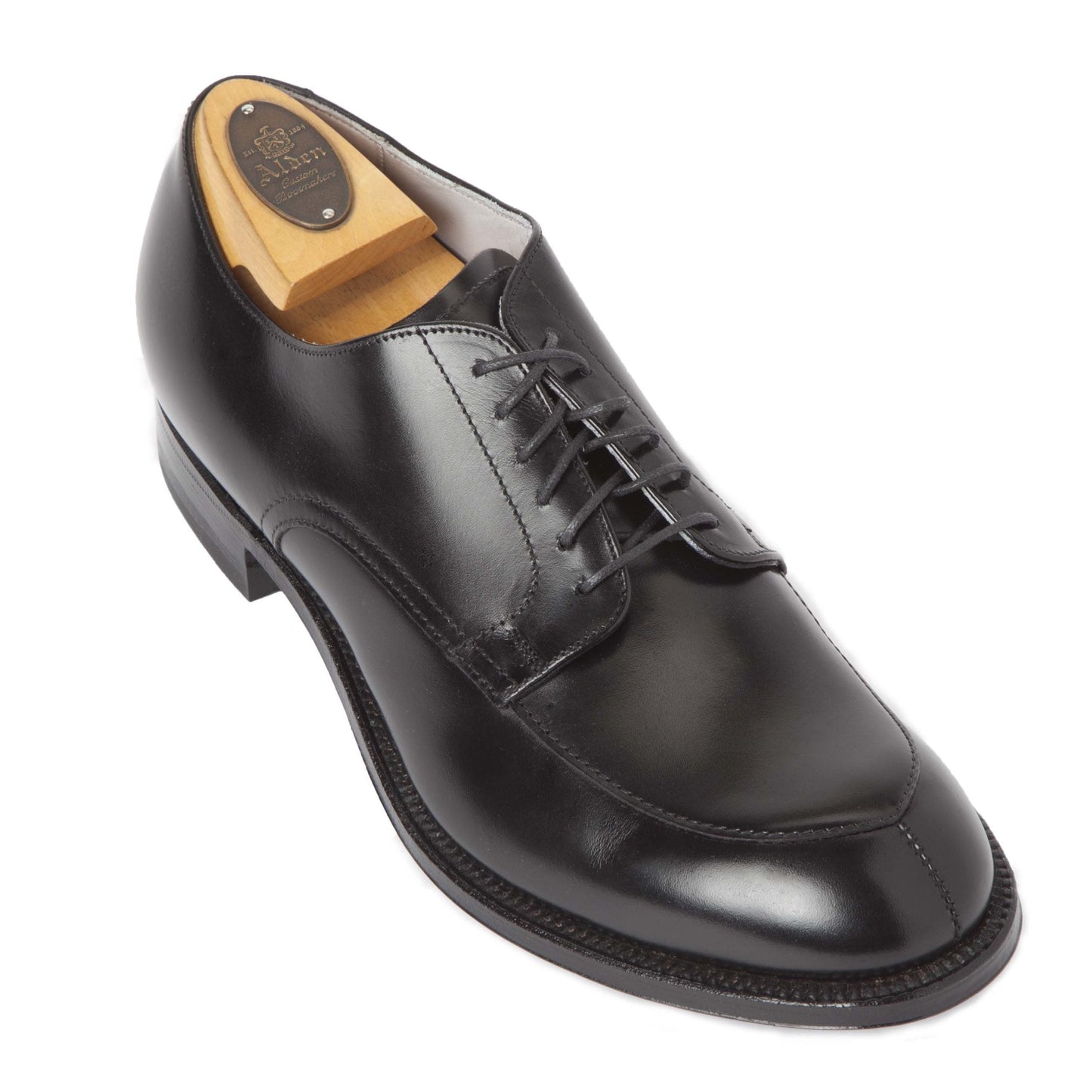 The Alden Madison 539 - Modified V-Tip in Black Calfskin is showcased with a wooden shoe tree. It features a rounded toe, lace-up design, polished finish, detailed edge stitching, and high arch support for ultimate comfort.