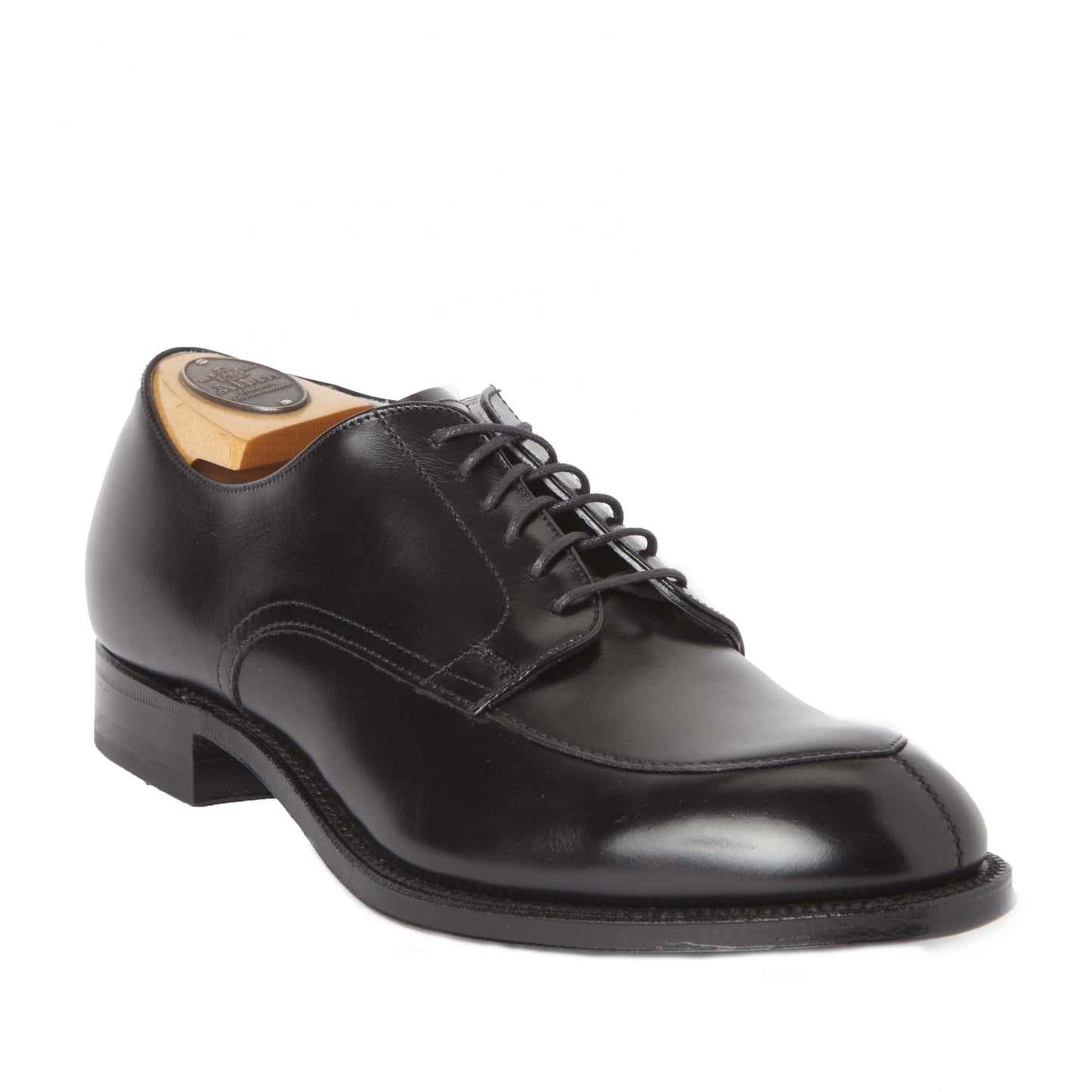 The Alden Madison 539 - Modified V-Tip in Black Calfskin is a polished, professionally crafted dress shoe. Featuring a smooth finish, wide toebox, and sturdy sole, it includes laces and a wooden shoe tree. Positioned at an angle on a white background, the shiny shoe exudes timeless elegance.