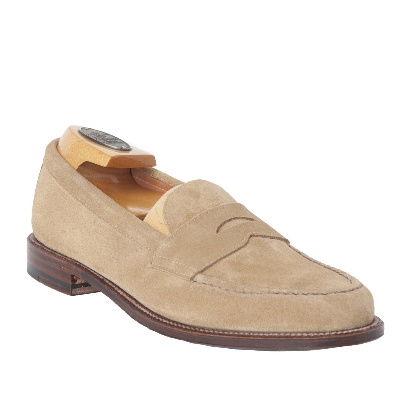 Alden Madisons 6244F Unlined Leisure Hand Sewn in Tan Suede features a classic penny strap and hand stitching, complemented by a brown leather sole. Inside, an angled wooden shoe tree enhances its sophistication.