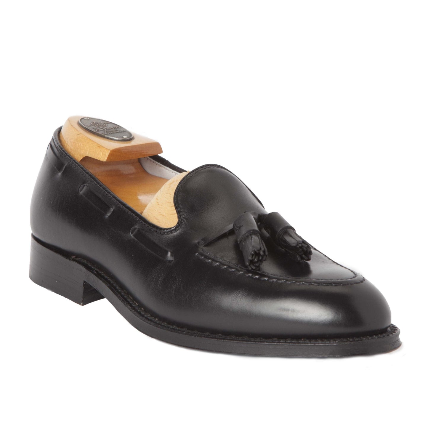 The Alden Madison 660 - Tassel Loafer in Black Calfskin rests against a plain background. Crafted on the sleek Aberdeen Last, it has a polished finish and comes with a beige shoe tree to maintain its shape.
