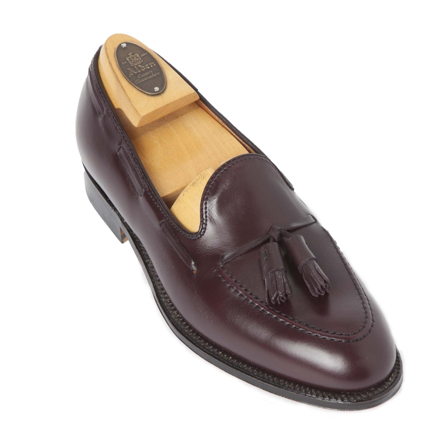 The 663 - Tassel Loafer in Burgundy Calfskin by Alden Madison features a polished finish, tassels on the upper, and a wooden shoe tree insert. Designed with the classic Aberdeen Last, it offers a sleek silhouette and low heel.