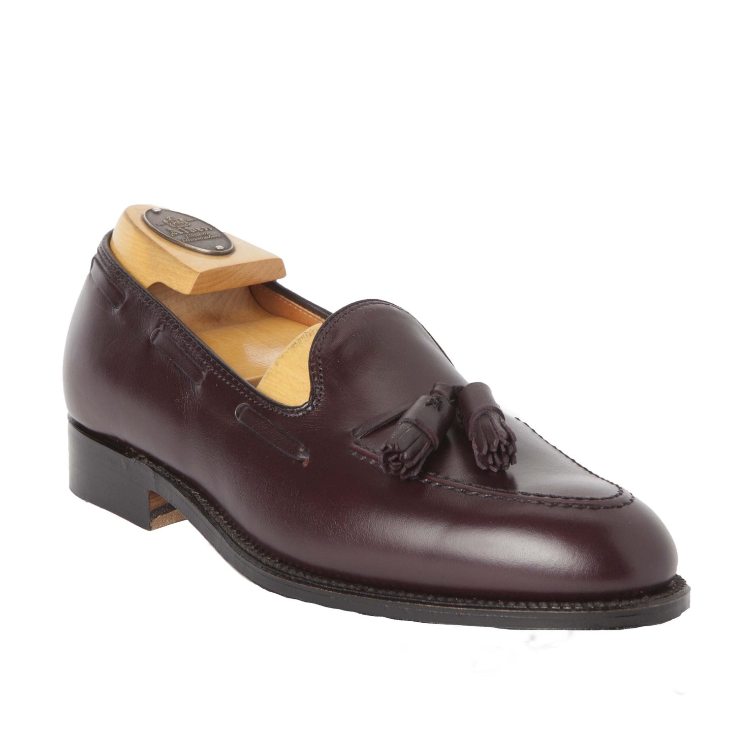 The Alden Madison 663 - Tassel Loafer in Burgundy Calfskin is a polished, dark burgundy shoe with tassels, designed on the Aberdeen Last. It features a low heel, leather sole, and includes a wooden shoe tree, elegantly displayed against a plain white background.