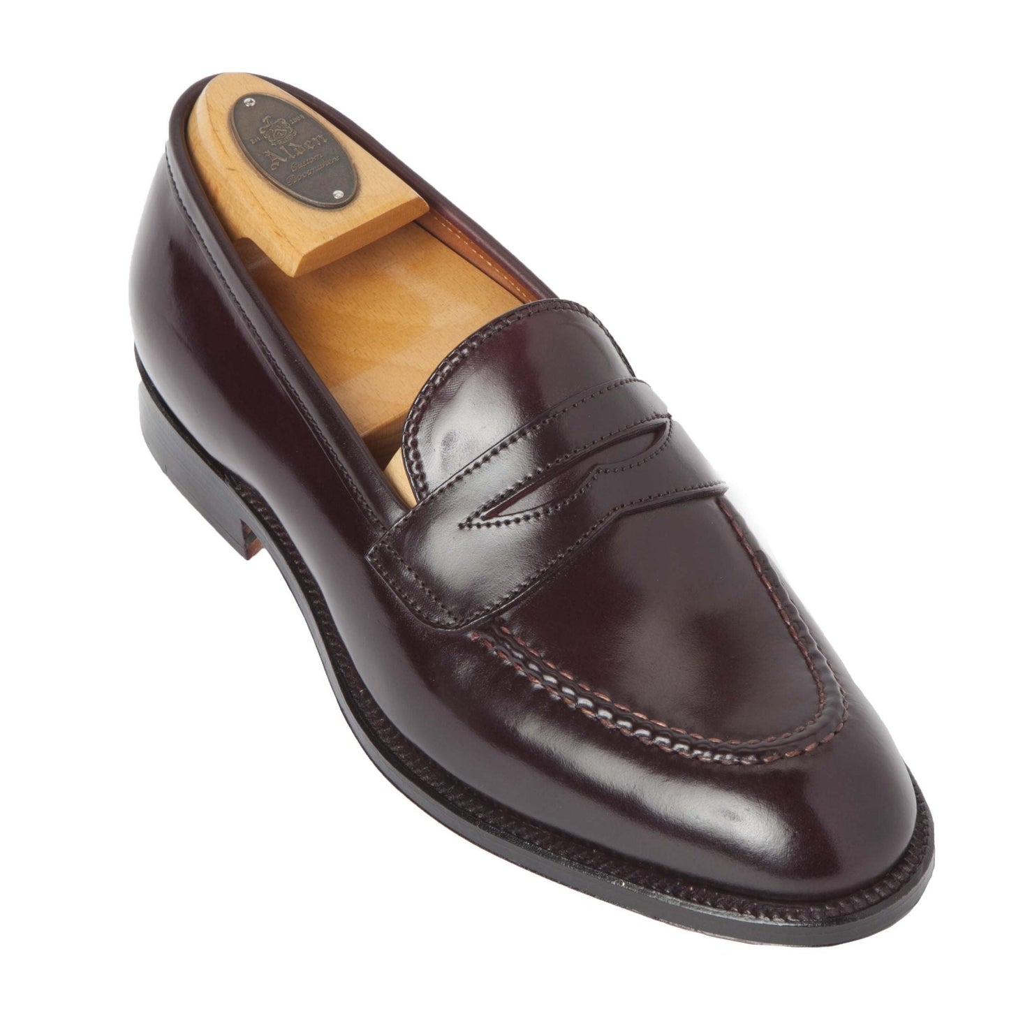 Aldan Madisons 67169 - High Vamp Loafer in Color 8 Shell is a single dark brown leather penny loafer with a wooden shoe tree inside, isolated on white. It boasts Shell Cordovan leather, classic design, hand stitching, and a polished finish.