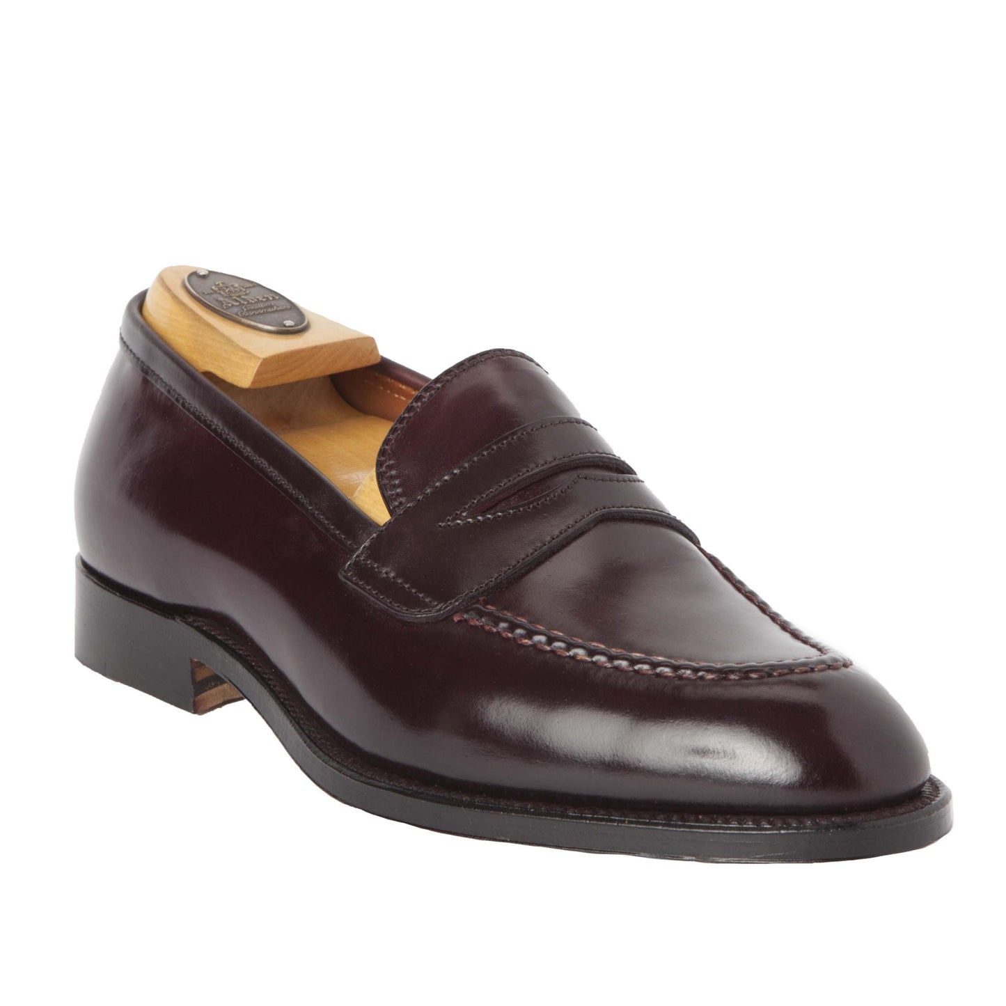 The Alden Madison 67169 High Vamp Loafer in Color 8 Shell is a sleek, dark brown leather shoe with a polished finish. It features a classic penny slot design, low heel, and fine hand stitching. A wooden shoe tree is included to maintain its shape.