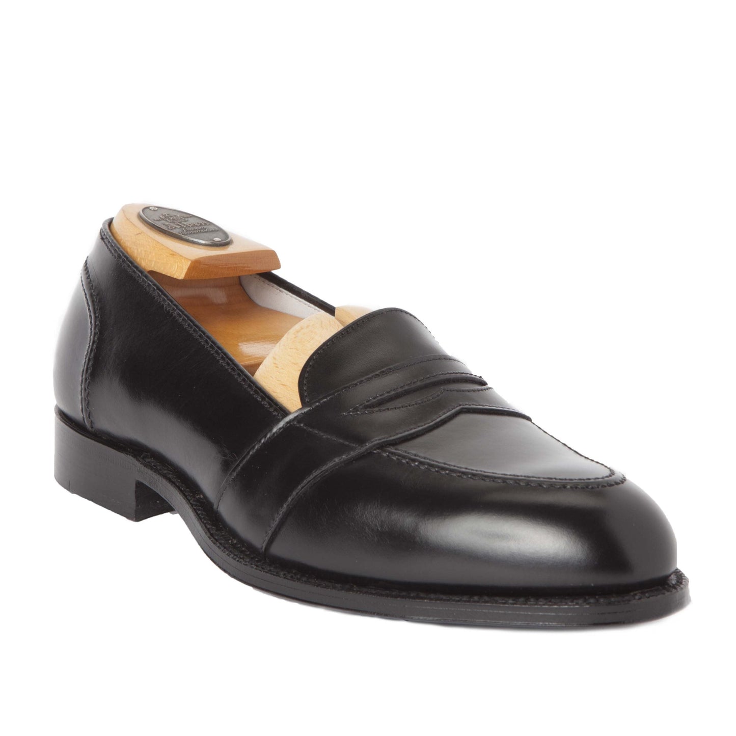 The Alden Madison 681 - Full Strap Loafer features black calfskin with a polished finish on the Aberdeen Last. This elegant design includes a wooden shoe form and classic stitching against a white background.