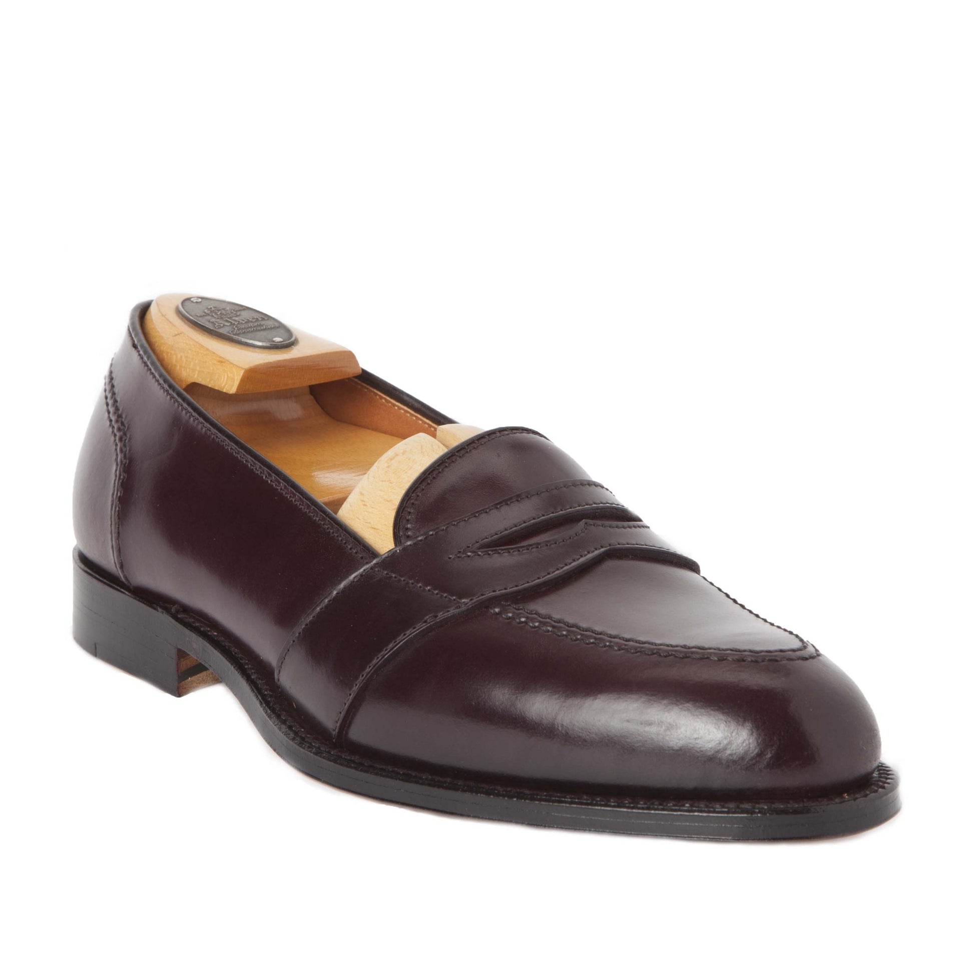 The Alden Madison 684 - Full Strap Loafer in Color 8 Shell is showcased at an angle on a white background. This dark brown leather loafer features a penny slot detail, a sleek leather outsole, and an Aberdeen Last for comfort. A wooden shoe tree maintains its shape.