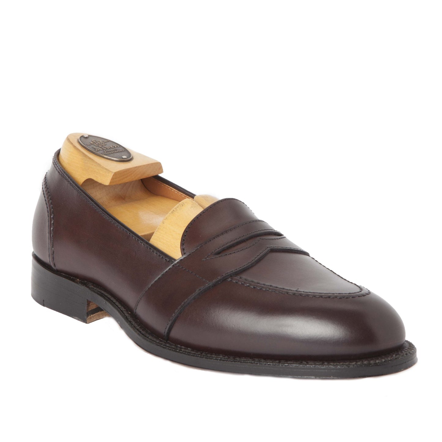 The Alden Madison 686, a dark brown calfskin loafer with a penny slot design and wooden shoe tree insert crafted on an Aberdeen last, sits against a white backdrop. Its black leather sole exhibits intricate stitched detailing.