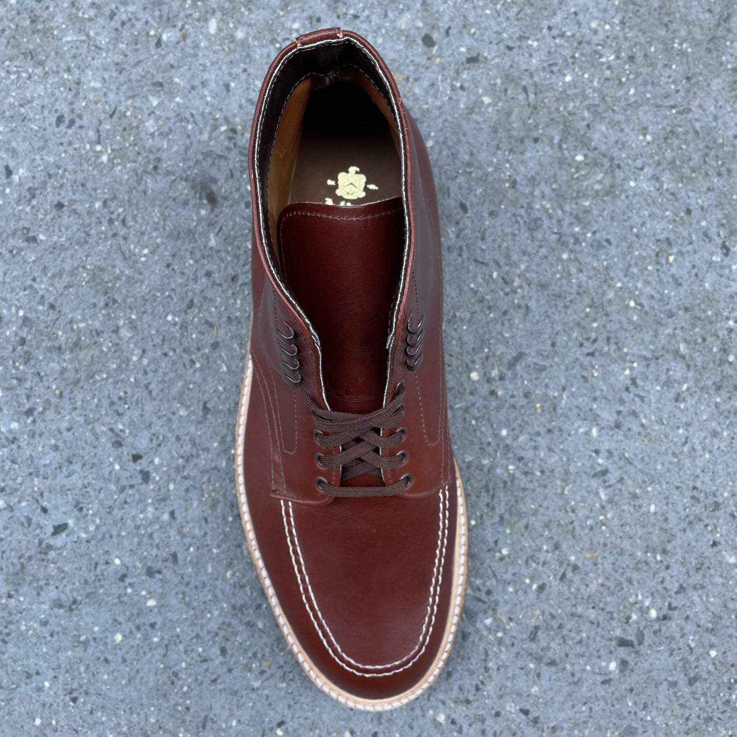A single Alden Madison 405C - Original 405 Indy Boot with detailed stitching and decorative insole emblem is displayed on a textured gray surface, featuring a rugged Commando Sole.