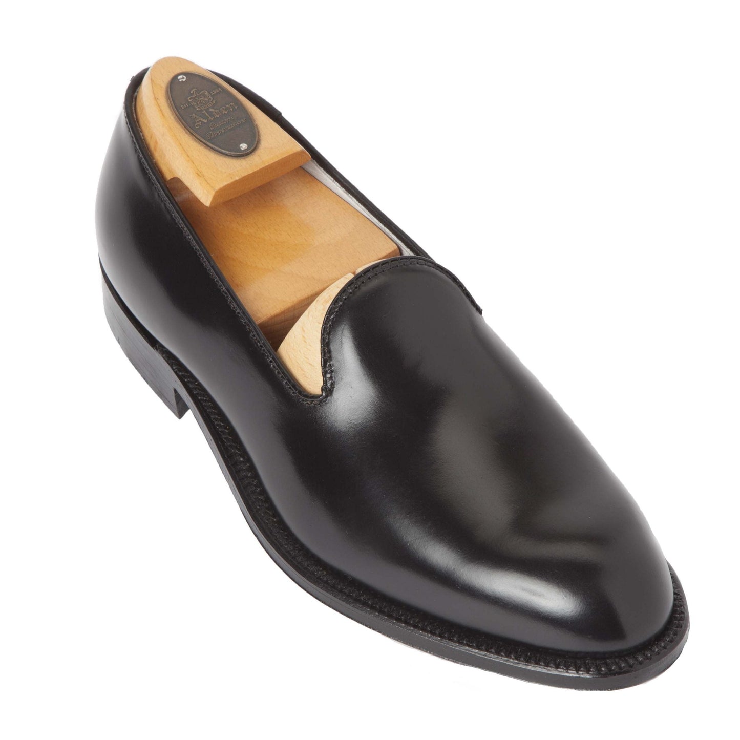 The Alden Madison 8815 is a black shell cordovan plain toe slip-on, featuring a wooden shoe tree and designed on the Aberdeen Last to maintain its elegant shape.