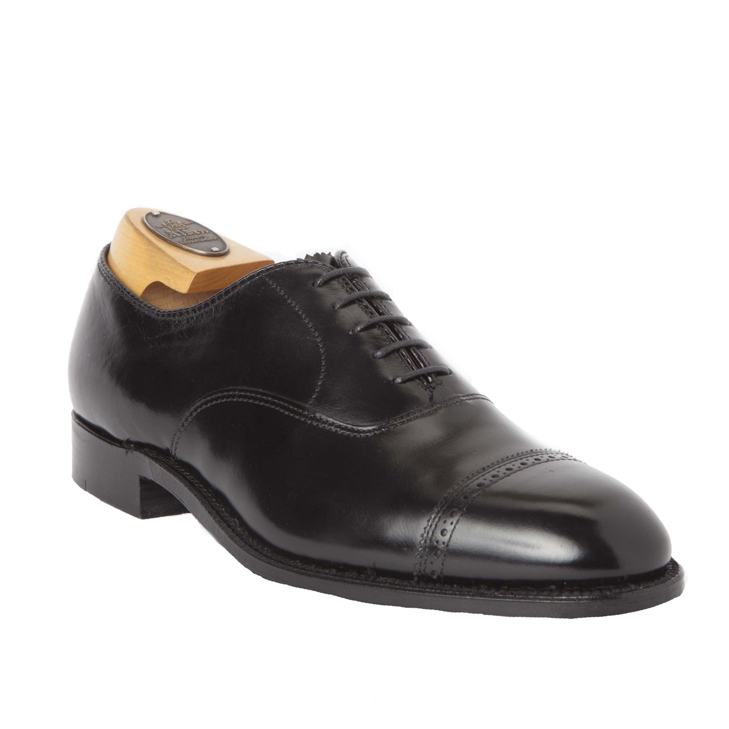 The Alden Madison 901 - Straight Tip Bal in Black Calfskin is a polished dress shoe with cap toe design, decorative stitching, and black laces. It features a sleek leather sole, low heel, wooden shoe tree insert and is crafted on the Hampton Last.