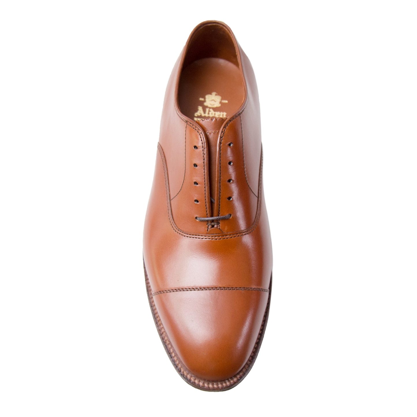 The Alden Madison 9062 Straight Tip Bal in Burnished Tan Calfskin is a sophisticated brown leather dress shoe with laces, Hampton Last, cap toe, intricate edge stitching, and a logo inside. It features a polished finish and rests on a refined single oak leather sole.