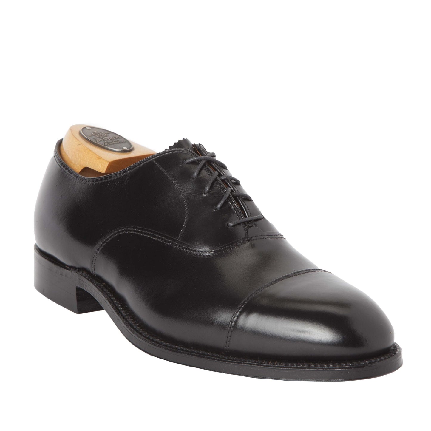 The Alden Madison 907 - Straight Tip Bal in Black Calfskin oxford showcases a polished finish, cap toe design, black laces, and a Leather Sole, complete with a wooden shoe tree. Set against a plain white background.