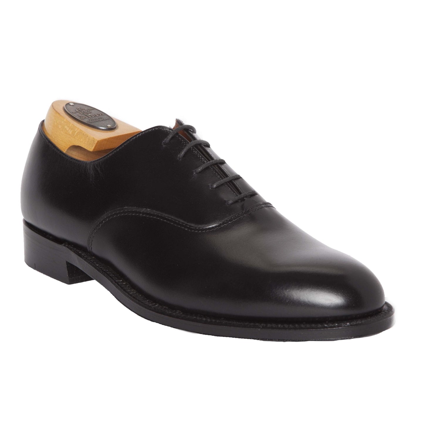 The Alden Madison 932 - Plain Toe Bal in Black Calfskin showcases polished black Oxford elegance, featuring closed lacing with a wooden shoe tree. Designed on the Aberdeen Last with a low heel and Single Oak Leather Sole, the shoe’s sleek silhouette is artfully displayed from side to front.