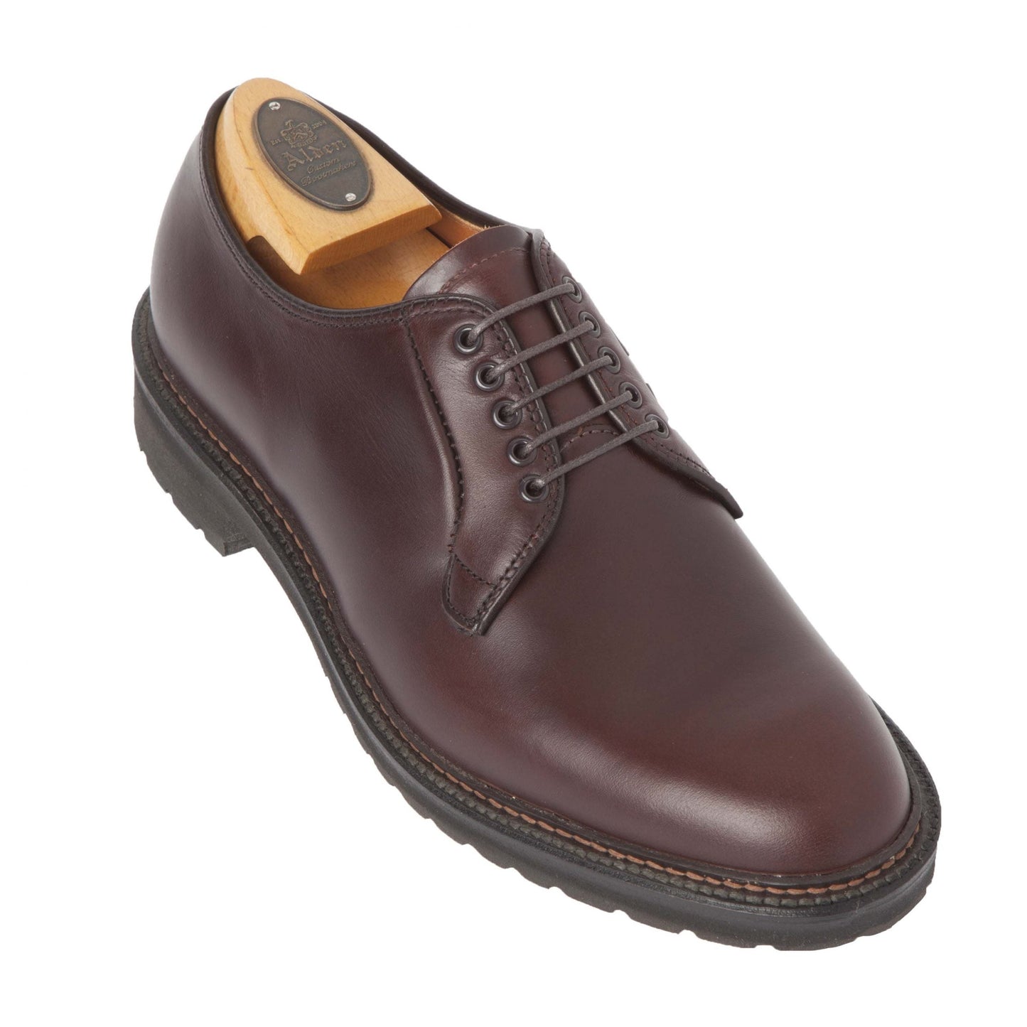 The Alden Madison 9432S - Plain Toe Blucher in Brown Chromexcel, crafted with a black lug rubber sole and black laces, is elegantly displayed at an angle on a white background. A wooden shoe tree nestled inside maintains its shape and fits the Barrie last design.