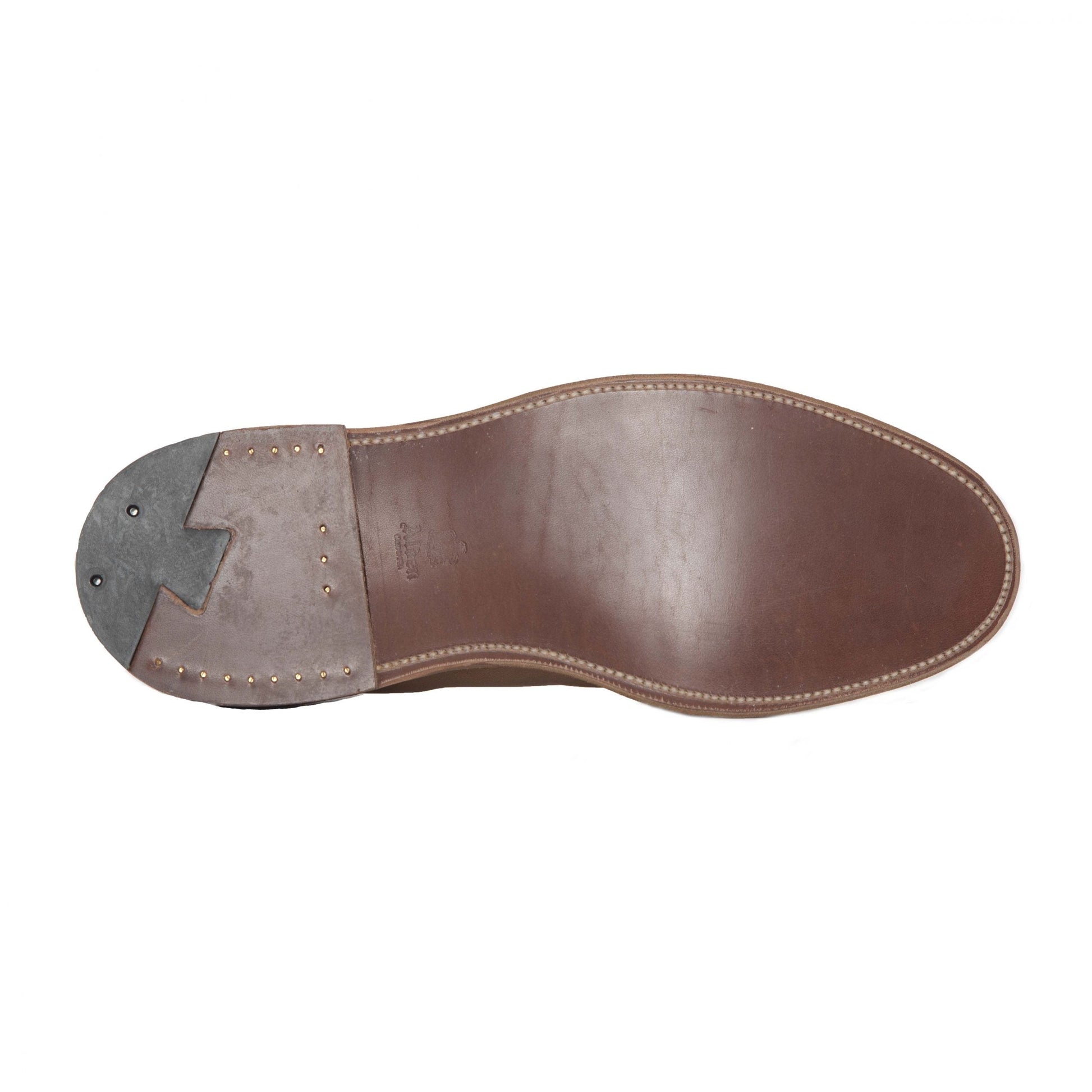 The image displays the underside of a brown suede Flex Penny Loafer by Alden Madison, featuring edge stitching. Crafted on a Copley Last, the heel is reinforced with darker material and metal studs, blending style and durability.