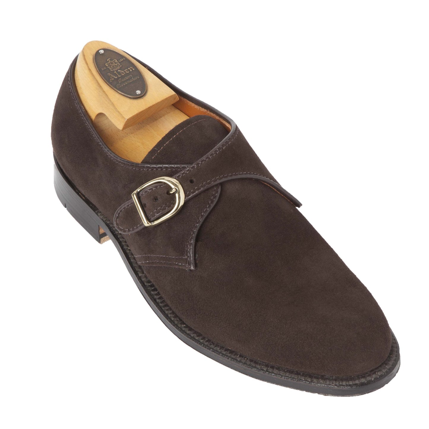 The Alden Madison 953 Monk Strap in Brown Suede features a gold buckle, smooth leather sole, and is crafted on the Aberdeen Last. Displayed with a wooden shoe tree, its sleek design highlights its formal style.