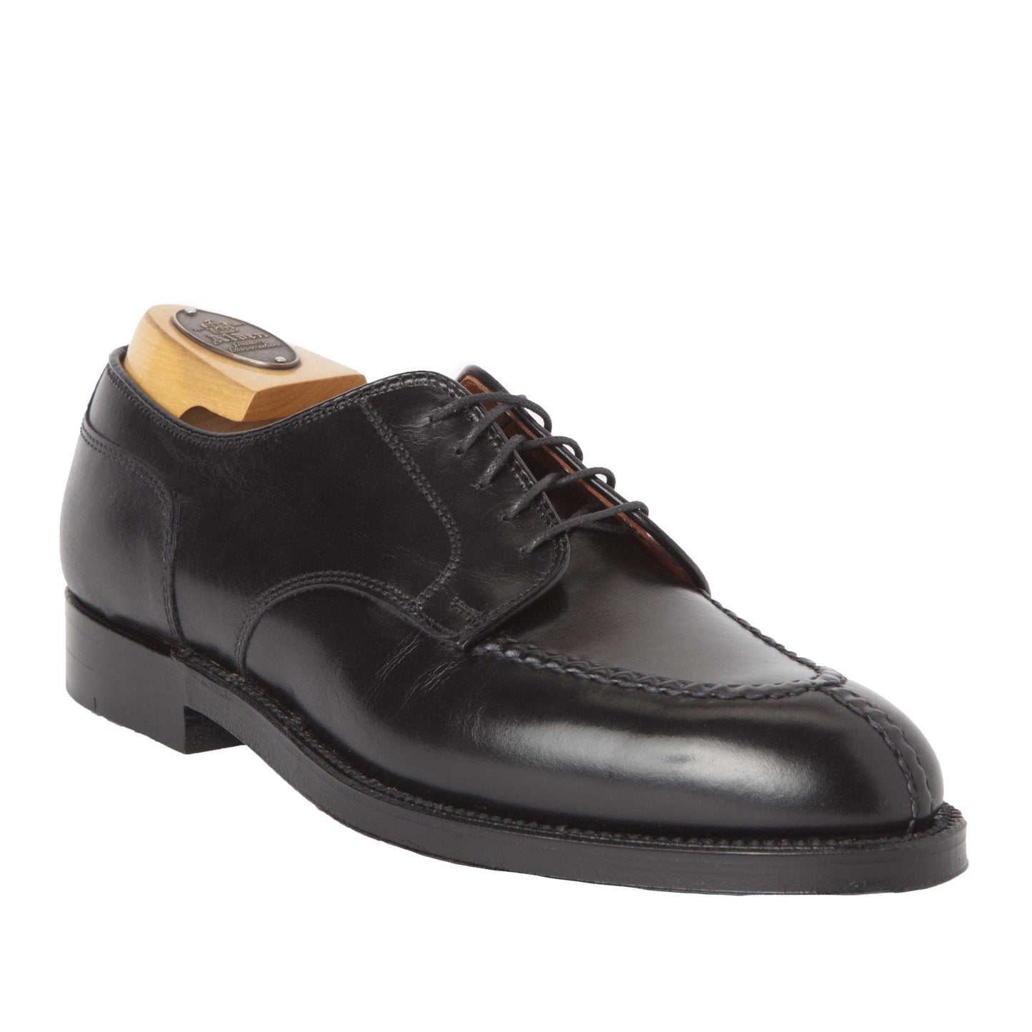 The Alden Madison 961 Norwegian Split Toe Blucher is a black calfskin dress shoe with intricate toe stitching, featuring a low heel, laces on an Aberdeen Last, and a durable Double Oak Leather Outsole. Its fitted with a wooden shoe tree to maintain its shape.
