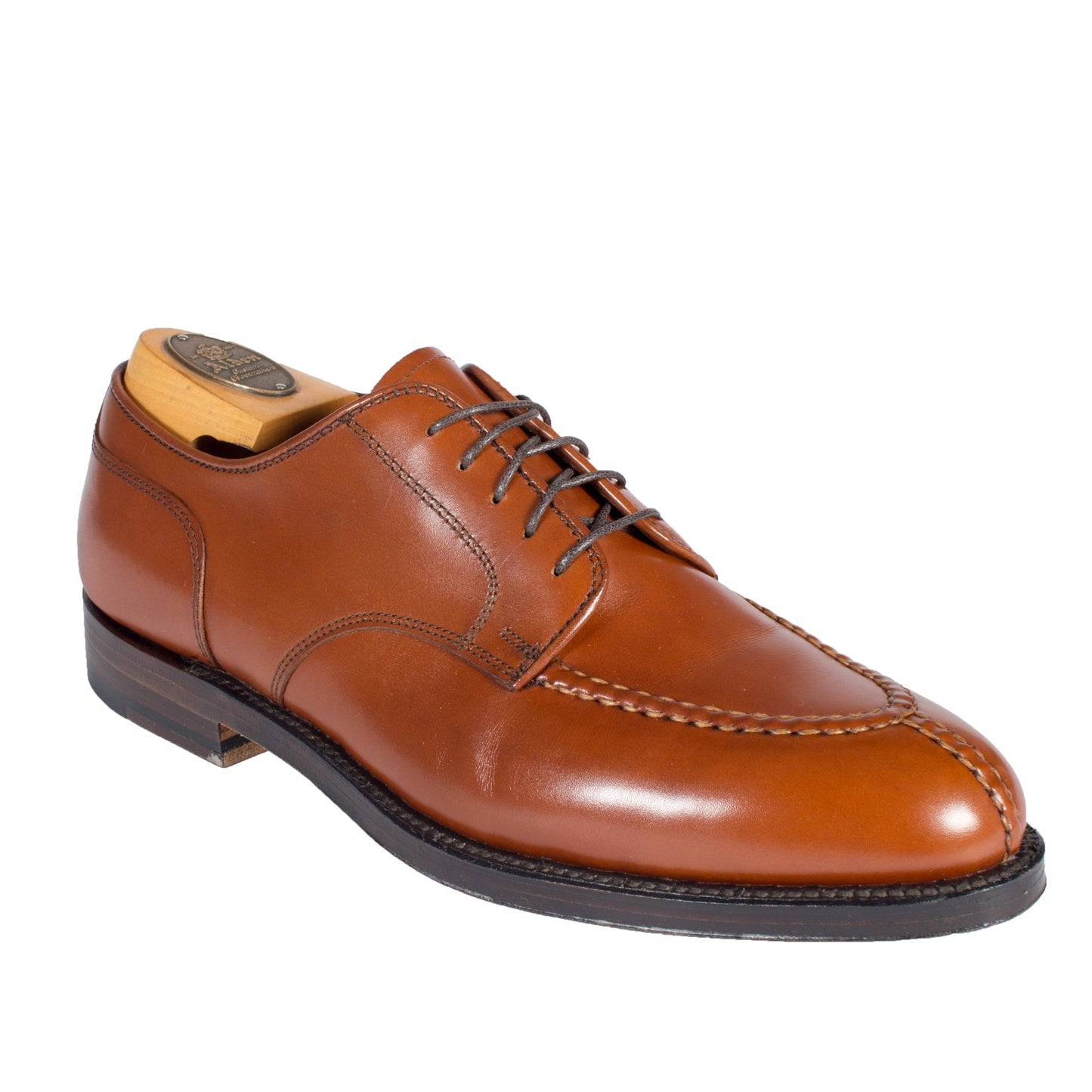 The Alden Madison 962 is a brown leather dress shoe featuring a polished burnished tan calf, moc toe design, and intricate stitching. It has black soles on an Aberdeen Last and is displayed with a shoe tree on a white background.