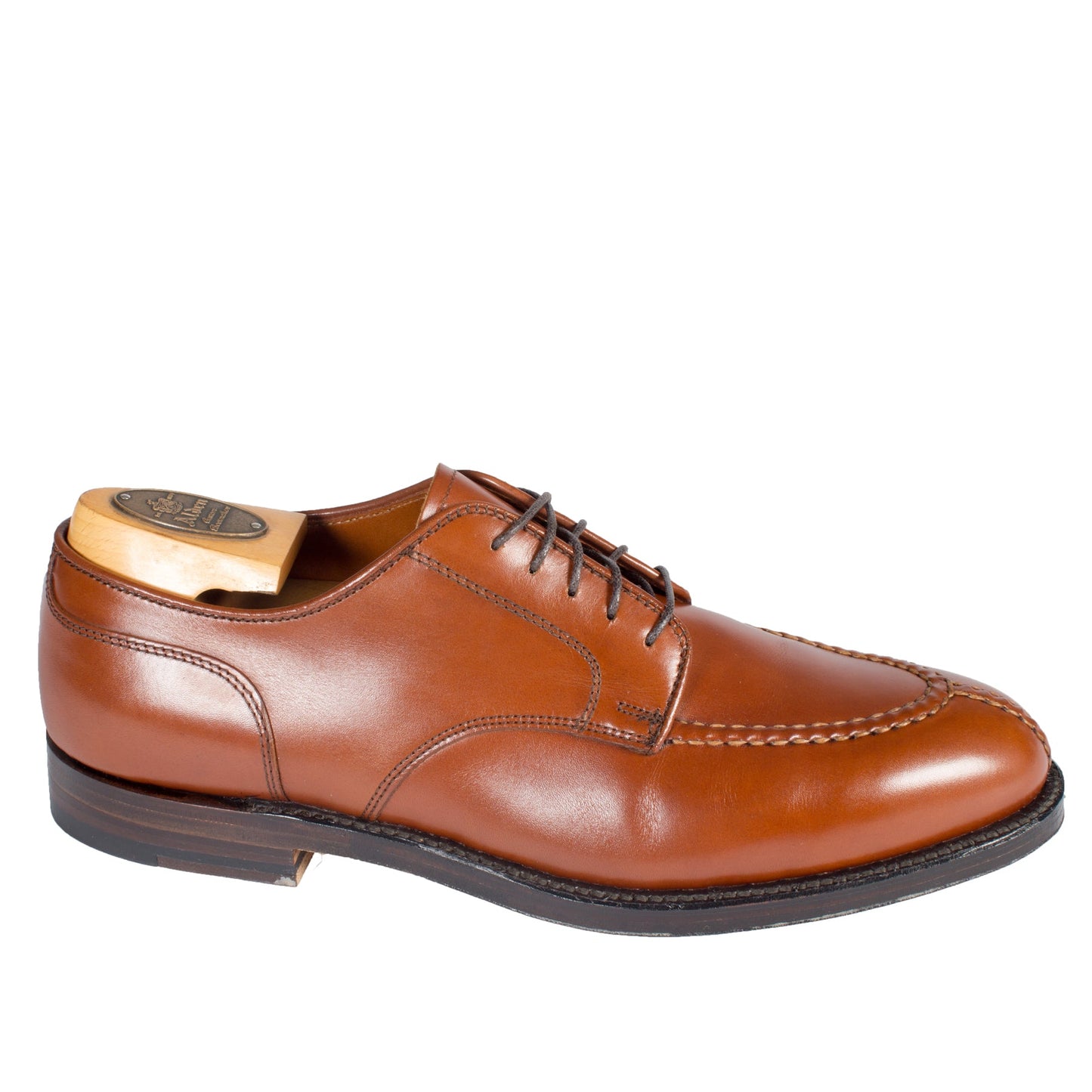 The Alden Madison 962 - Norwegian Split Toe in Burnished Tan is a single brown leather dress shoe with a classic lace-up design, toe stitching, and a wooden shoe tree. It features a dark brown Double Leather Sole and is elegantly angled.
