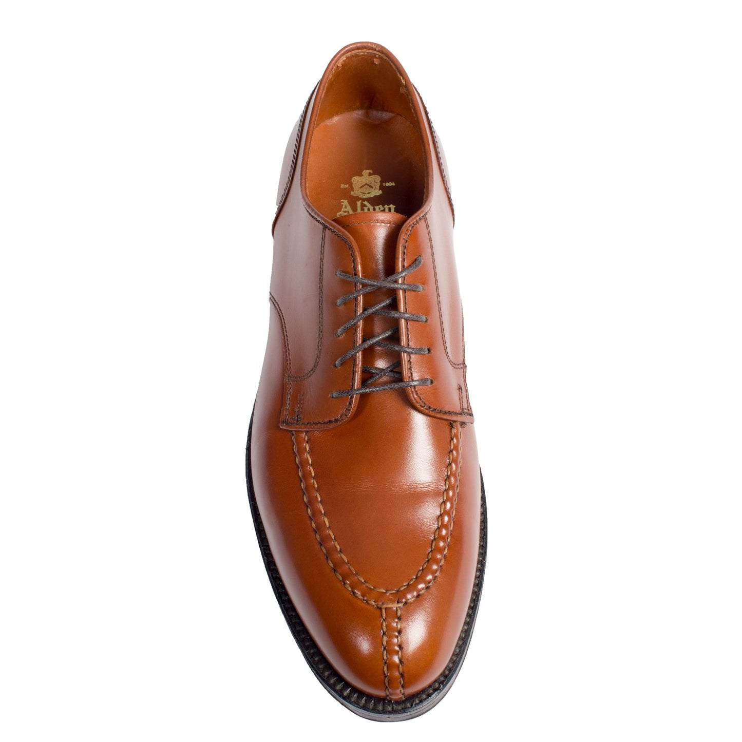 A top-down shot showcases the Alden Madison 962 - Norwegian Split Toe shoe in polished burnished tan calf leather with intricate stitching, dark brown laces, and a double leather sole on the Aberdeen Last. Interior branding is visible on the insole against a white backdrop.