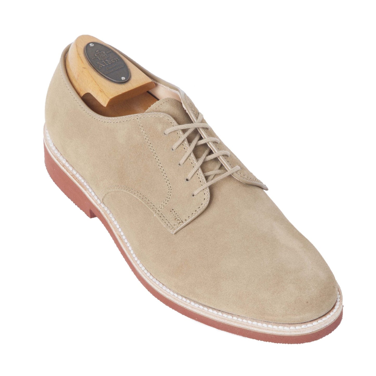 The Alden Madison 96803 - Dirty Buck in Tan Suede is a lightweight derby shoe featuring white stitching and a distinctive red rubber sole, displayed with a wooden shoe tree to accentuate its sleek design.