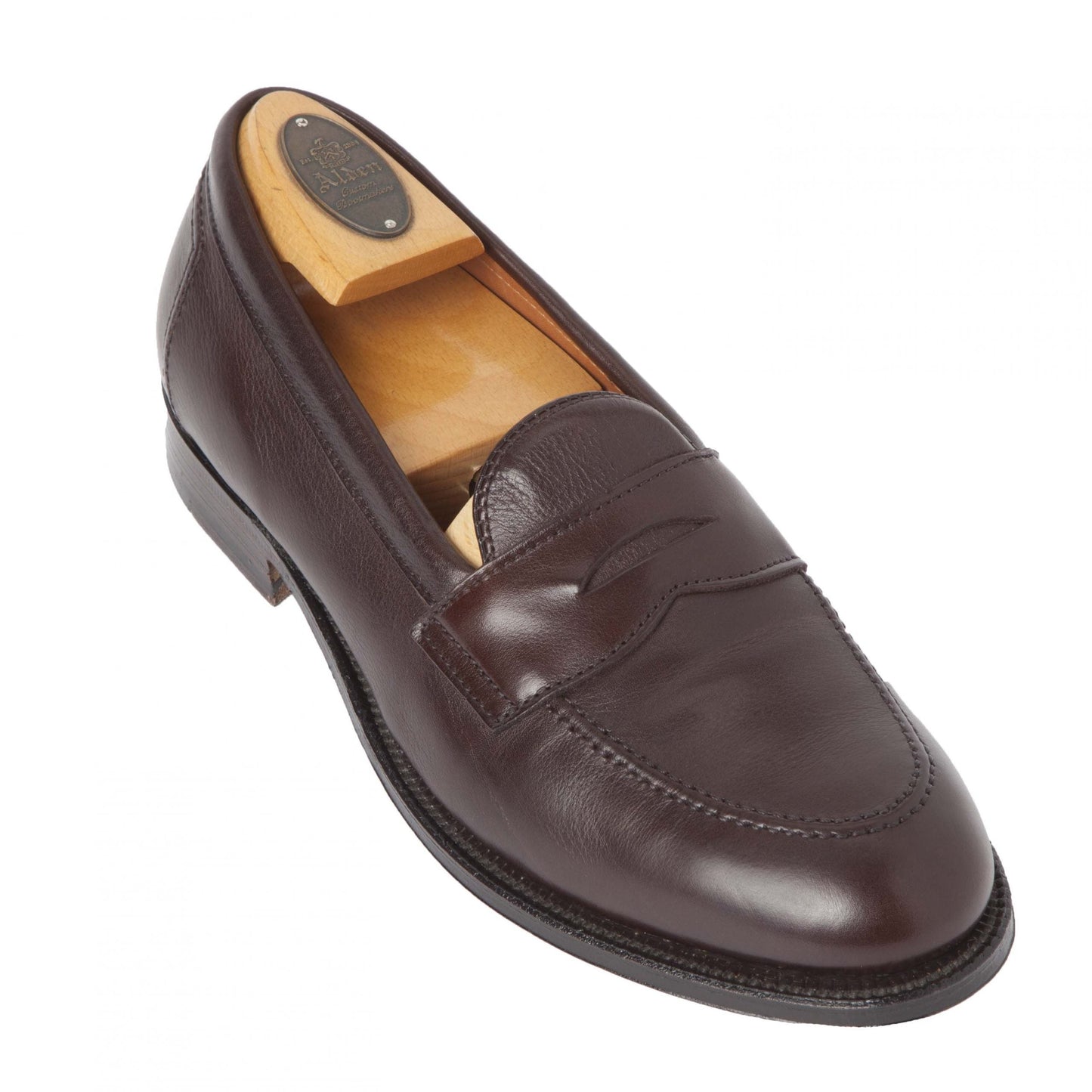 The Alden Madison 9694F Flex Penny Loafer in Brown Lady Calf, crafted on a Copley Last with fine stitching and a penny slot design, rests on a white background. Its shape is maintained by the wooden shoe tree inside.