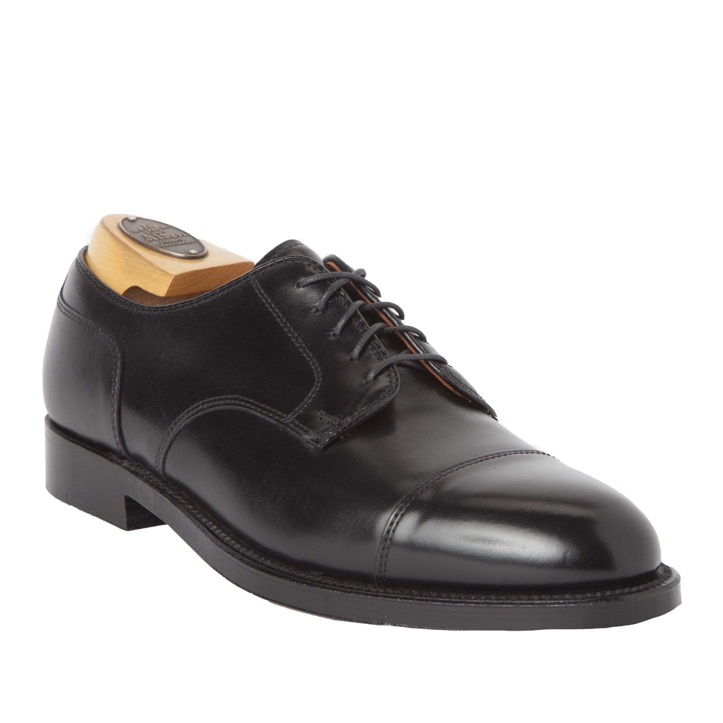 The Alden Madison 971 - Cap Toe Blucher in Black Calfskin is crafted from premium black calfskin and showcases a sleek design with a cap toe, black laces, and a Double Oak Leather Sole. It comes with a wooden shoe tree inside to enhance its polished appearance and classic style.