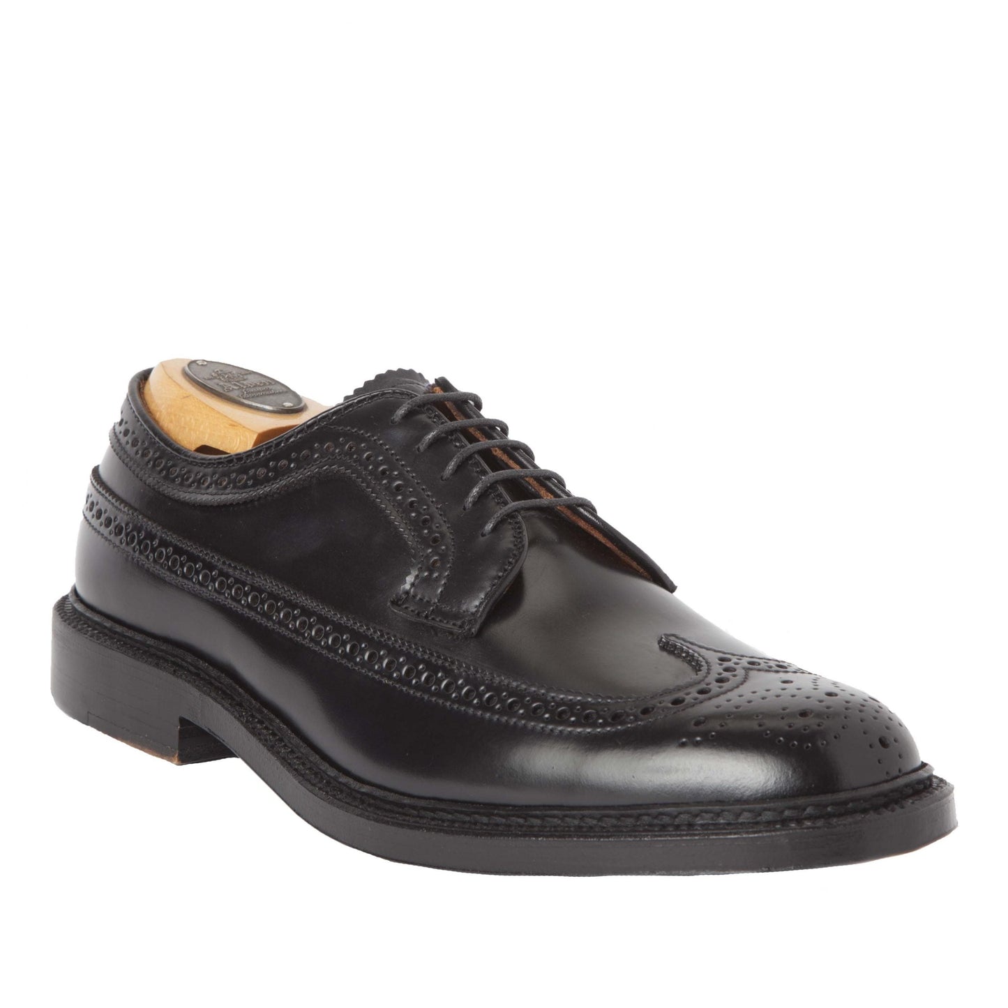 The Alden Madison 9751 - Long Wing Blucher in Black Shell Cordovan is a polished black leather brogue on the Barrie Last, featuring intricate perforations, laces, and a Double Oak Leather Sole. Displayed with a wooden shoe tree to preserve its shape.