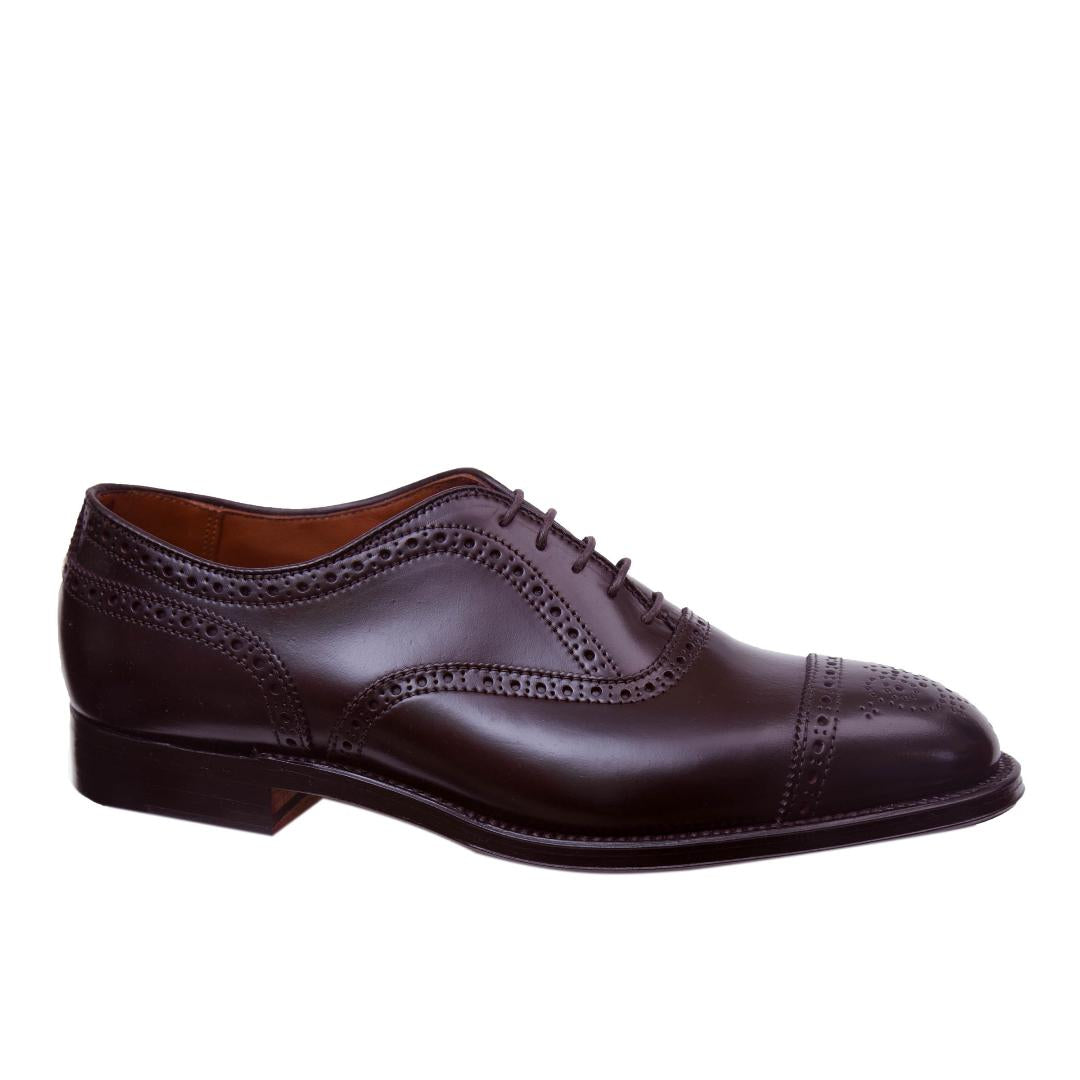 The Alden Madison 9854 Medallion Cap Toe Bal in Color 8 Shell Cordovan is a dark brown dress shoe featuring brogue detailing, closed lacing, a low heel, and sleek toe cap, crafted on the Hampton Last against a white background.