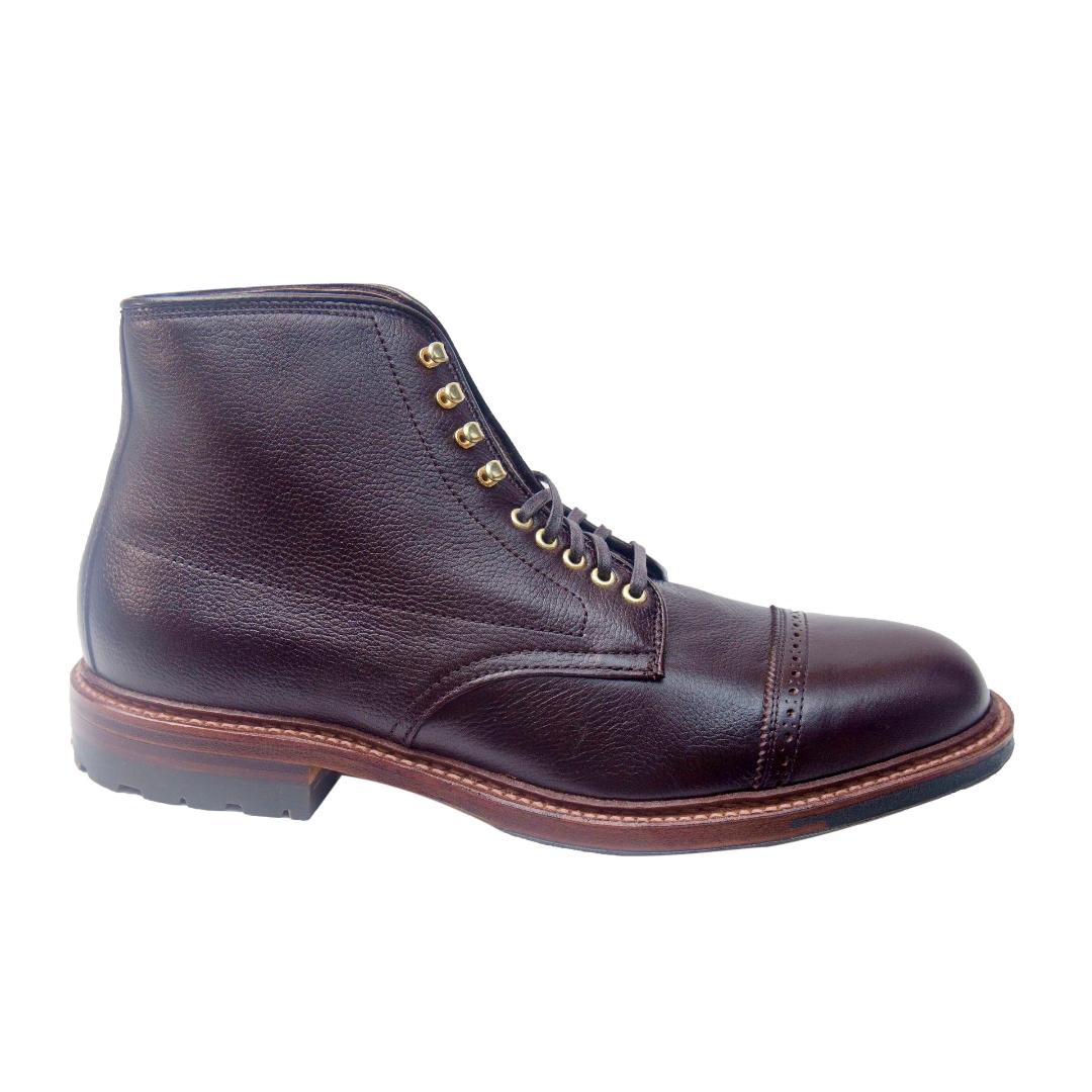 Meet the D9819HC - Jumper Boot in Regina Brown Grain by Alden Madison, an ankle-length boot featuring a cap toe, gold eyelets, black laces, and a rugged Commando Sole with brown accents. Built on the Barrie Last for timeless elegance against a plain white backdrop.
