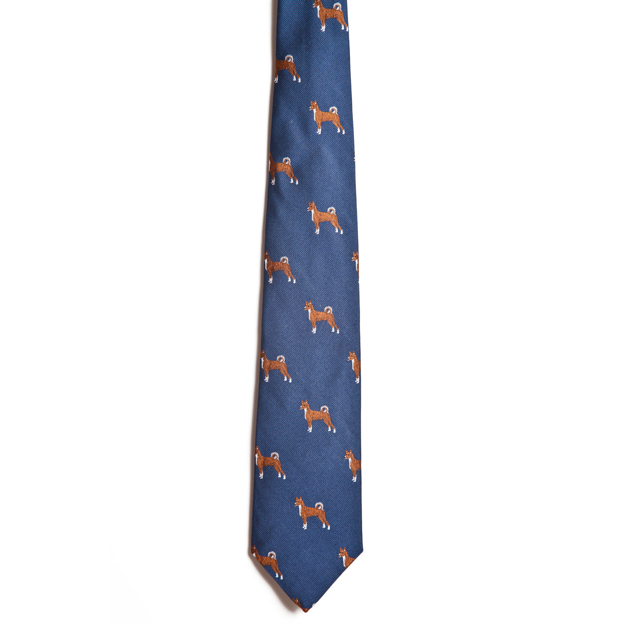 The Alden Madison Basenji tie is a blue silk jacquard necktie featuring a repeating pattern of small brown and white Basenji dogs, shown against a white background.