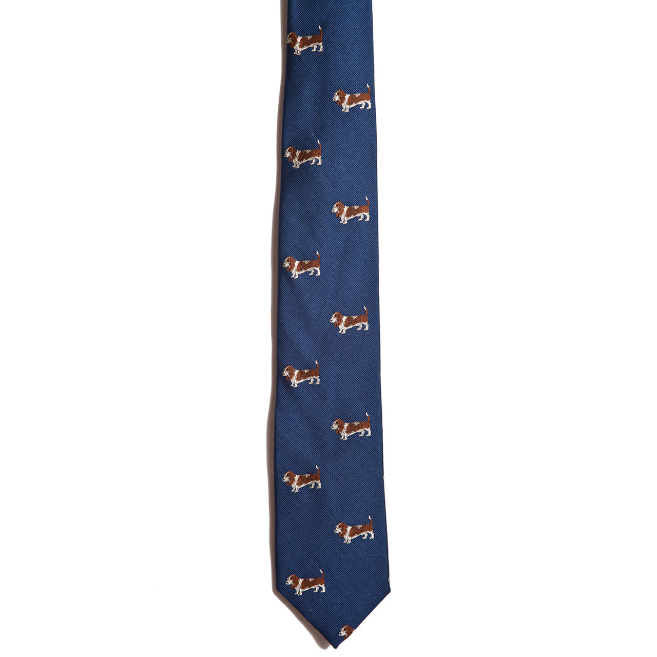 Alden Madisons Basset Hound tie, made from 100% silk, features a delightful pattern of small brown and white dogs. The charming figures are vertically aligned on a plain white background, highlighting the intricate jacquarding technique.