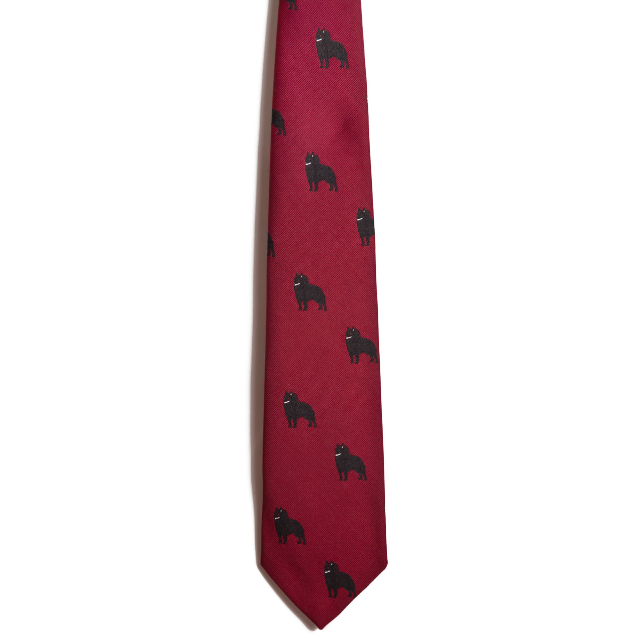 The Schipperke necktie by Alden Madison is crafted from 100% silk and features a jacquarded pattern of small black bear silhouettes evenly spaced across its red fabric.