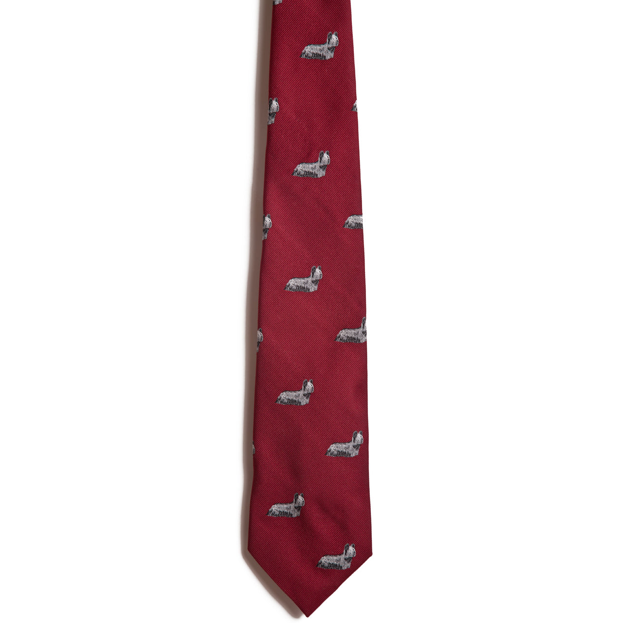 Alden Madison’s Sky Terrier is a red jacquard dog necktie featuring a repeating pattern of small embroidered gray and white dachshunds, displayed on a white background.