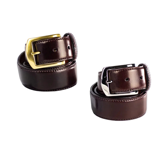Two Alden Madison 38mm Color 8 Shell Cordovan belts are shown—one with a nickel buckle, one with a brass buckle—both neatly coiled on a white surface.