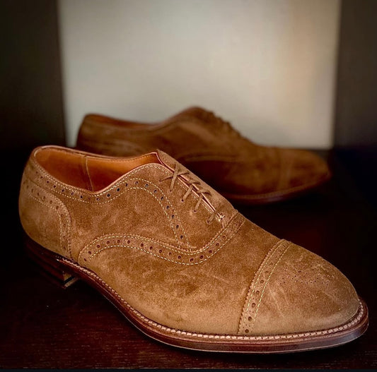 Alden Madison 51670F Medallion Cap Toe Bal dress shoes in brown snuff suede, shown on a dark surface with one shoe in focus and the other slightly blurred in the background.
